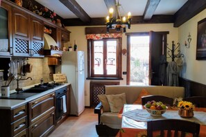 Eine Küche mit Holzausstattung, ein Essbereich mit Tisch für zwei Personen und ein Fenster mit Blick ins Freie.