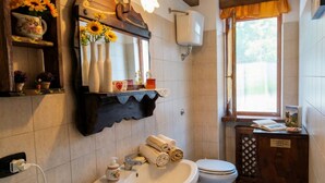 Une salle de bain équipée d’un lavabo, d’un miroir, de toilettes et d’une fenêtre donnant sur un paysage agréable.