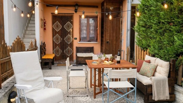 Un espace extérieur accueillant, aménagé avec une table en bois, des chaises et des guirlandes lumineuses.