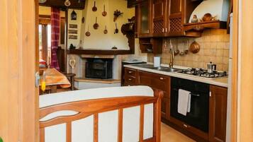 A kitchen with wooden cabinets, a stove, and hanging pots.
