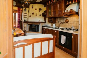 Una cocina con armarios de madera, una estufa y ollas colgantes.