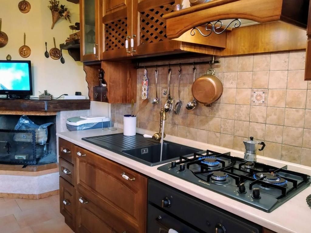 Une cuisine équipée d’une cuisinière à gaz, de meubles de rangement en bois et d’ustensiles suspendus.