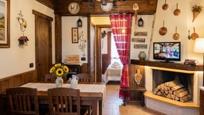 Une pièce chaleureuse avec une table en bois, des chaises, une cheminée et un téléviseur.