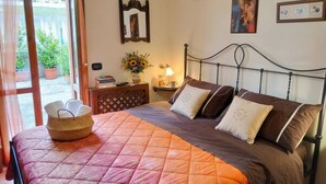 Ein Schlafzimmer mit einem Bett, einem Nachttisch mit Lampe, einem Spiegel und gerahmten Bildern an der Wand.