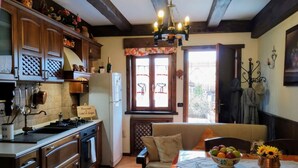 Eine Küche mit Holzausstattung, ein Essbereich mit Tisch für zwei Personen und ein Fenster mit Blick ins Freie.