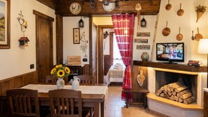 Ein gemütliches Zimmer mit einem Holztisch, Stühlen, einem Kamin und einem Fernseher.