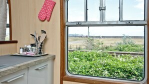 A kitchen with a window view of a field and a railway track. - Brunel Boutique Railway Carriage 5 (Dawlish Warren)