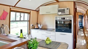 A kitchen with white cabinets, a microwave, and an oven. - Brunel Boutique Railway Carriage 5 (Dawlish Warren)