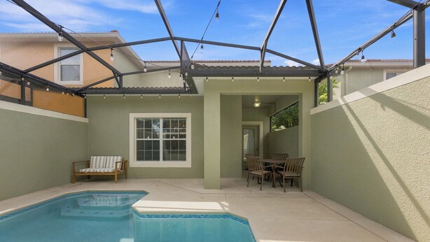 A swimming pool with a patio area, a covered seating area, and a view of a residential building.