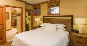 Relax in this spacious room with a large bed, wooden nightstands, and a window offering a view of the outdoors.