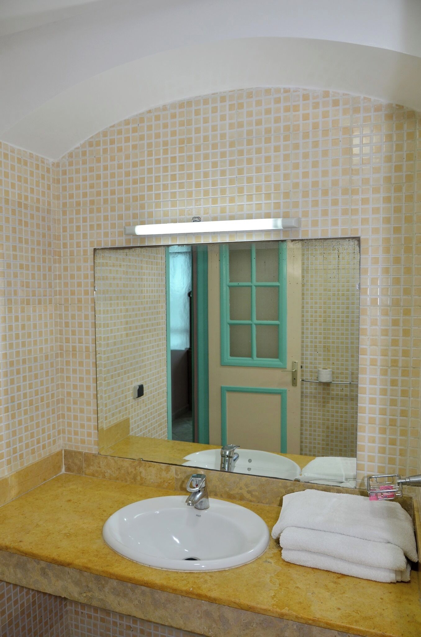 A bathroom with a sink, mirror, and a door with a green frame.