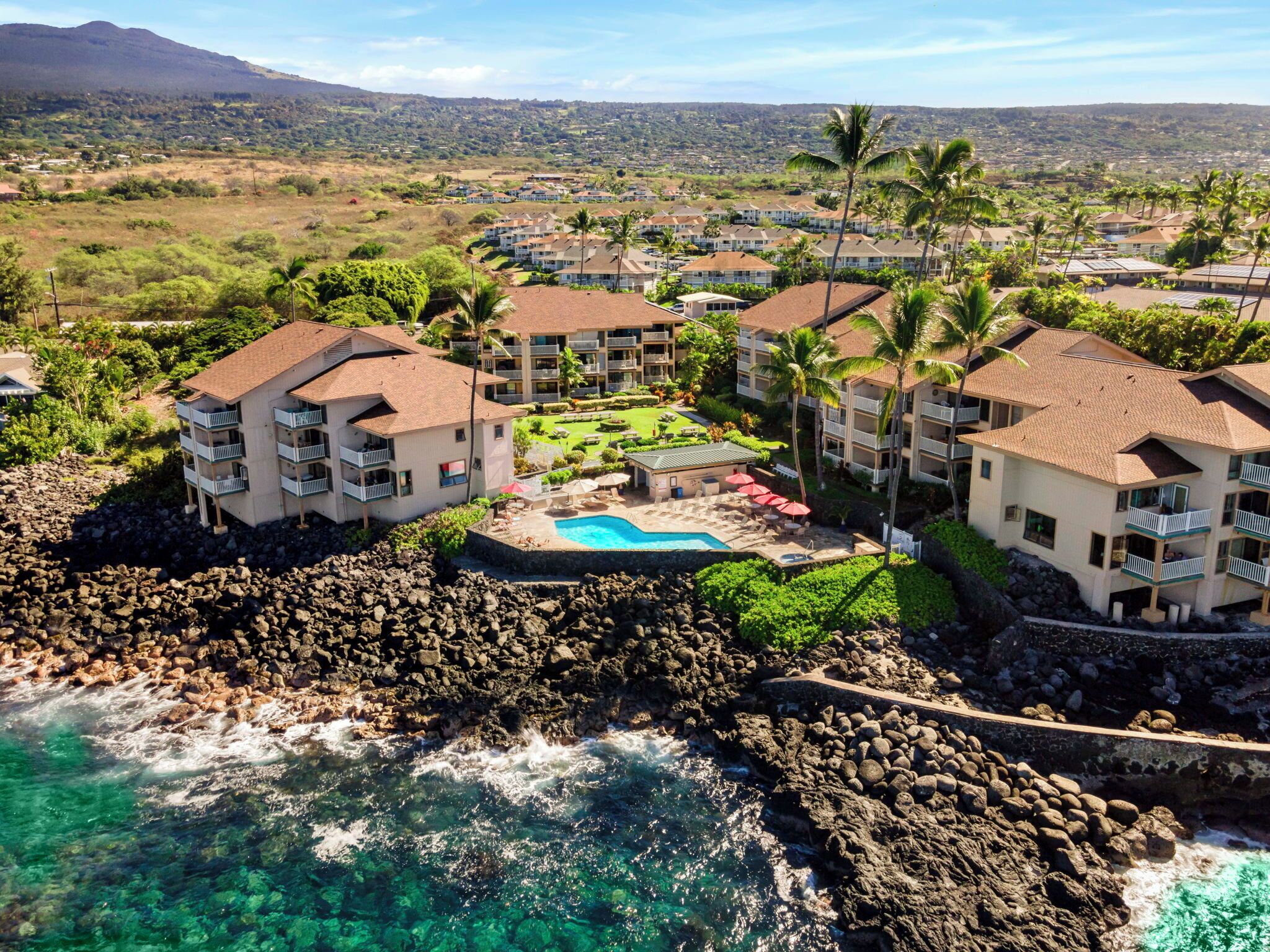 A resort with multiple buildings, a swimming pool, and a rocky shoreline.