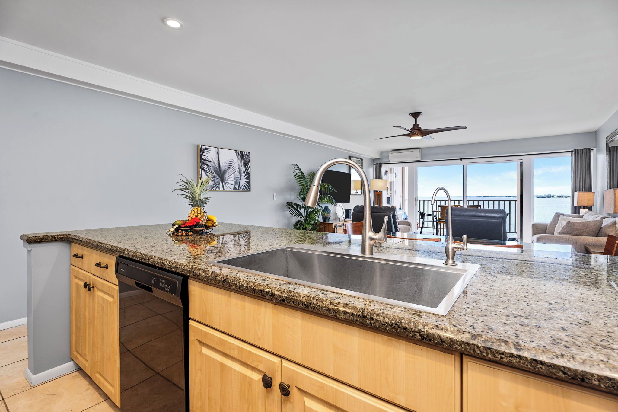 A modern kitchen with granite countertops, a stainless steel sink, wooden cabinets, and a dishwasher.