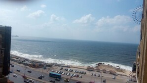 Un paisaje urbano costero con vista al mar, una calle concurrida y una noria grande.