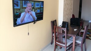 Un televisor montado en la pared en un comedor con sillas y una mesa de madera.