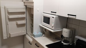 A compact kitchen with a built-in microwave, a coffee maker, and a small refrigerator. - central and beachfront apartment in Kühlungsborn East (Kühlungsborn)