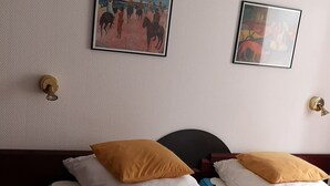 A double bed with white and blue bedding, two mustard pillows, and two framed artworks on the wall. - central and beachfront apartment in Kühlungsborn East (Kühlungsborn)