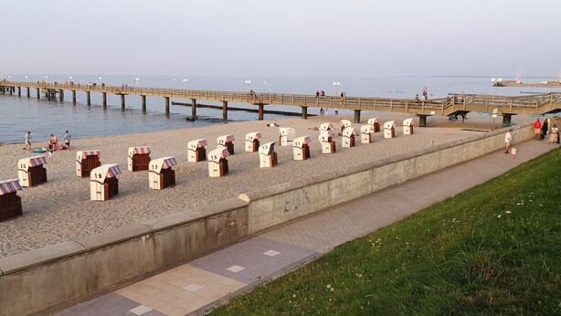 A beach with numbered beach huts, a pier, and a walkway. - central and beachfront apartment in Kühlungsborn East (Kühlungsborn)