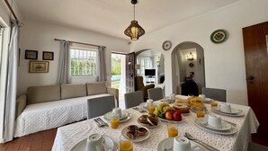 A dining area with a table set for breakfast, a sofa, and a view of the outdoors.