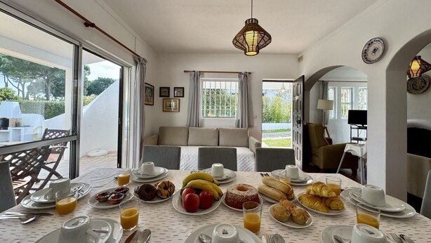 A dining area with a table set for breakfast, including plates, cups, and various food items.