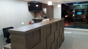 A reception desk with a modern design, a flat-screen TV mounted on the wall, and pendant lighting.