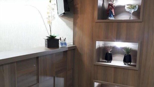 A corner reception desk with a wooden panel design, a potted orchid, and a small statue.