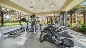 A covered outdoor gym area with treadmills, elliptical machines, and weight equipment.