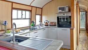 Eine kompakte Küche mit Spüle, Mikrowelle und Toaster. Ein Fenster sorgt für natürliches Licht und bietet einen Ausblick.