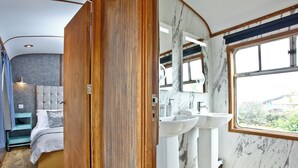 Ein modernes Badezimmer mit Holztür, Marmorwänden und einem großen Fenster.