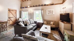 A cozy living room with a sofa, a coffee table, a television, and a dining area with chairs and a table. - 3 bedroom accommodation in Hollingbourne (Hollingbourne)