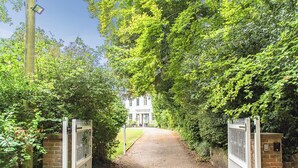A gravel pathway leading to a white building with a blue door, surrounded by lush greenery. - 3 bedroom accommodation in Hollingbourne (Hollingbourne)