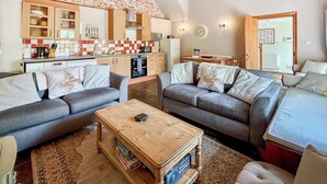 A cozy living room with two grey sofas, a wooden coffee table, and a kitchen in the background. - 3 bedroom accommodation in Hollingbourne (Hollingbourne)