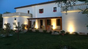 Una casa a due piani con un balcone, un portico coperto e un ingresso ben illuminato.