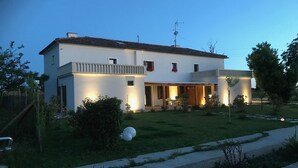 Una casa a due piani con un balcone, un prato curato e un vialetto che conduce all'ingresso.