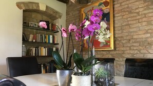 Un'area pranzo con un tavolo apparecchiato per due, circondata da scaffali di libri e un quadro.