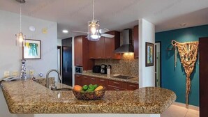 A modern kitchen with granite countertops, a built-in oven, and a hanging light fixture. - Beautiful Beach front condo Villa Magna (Nuevo Vallarta)