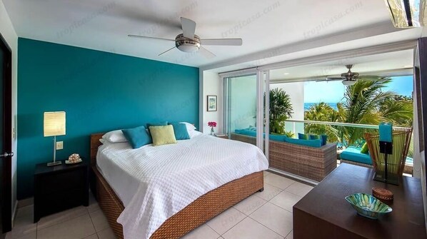 Une chambre à coucher comprenant un lit, une table de chevet, une table avec un bol, et un balcon avec du mobilier d’extérieur.