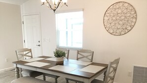 A dining room with a wooden table, four chairs, a bench, a chandelier, a window, and a decorative wall piece. - CHARMING 2 BDRM 2 BATH Sm Dog Friendly Patio Villa w/FREE WIFI (The Villages)