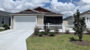A two-story house with a garage, a white picket fence, and a small tree in the front yard. - CHARMING 2 BDRM 2 BATH Sm Dog Friendly Patio Villa w/FREE WIFI (The Villages)