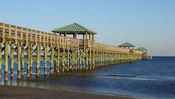 Un muelle de madera que se adentra en el agua, con una estructura de quiosco al final.