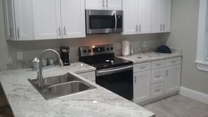 Una cocina moderna con armarios blancos, electrodomésticos de acero inoxidable y una encimera de mármol.
