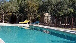 En rektangulär swimmingpool med en kant som är klädd med kakel, omgiven av ett staket.