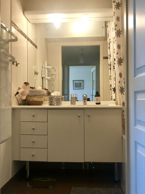 A bathroom with a white vanity, a towel rack, and a shower curtain.