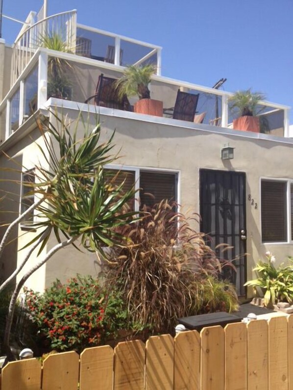 A two-story building with a balcony, potted plants, and a wooden fence. - Tropical House! Prime location!   Two story with decks and bbq patio.  (San Diego)