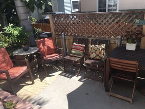 An outdoor patio area with wooden chairs and a small round table, surrounded by a wooden lattice fence. - Tropical House! Prime location!   Two story with decks and bbq patio.  (San Diego)