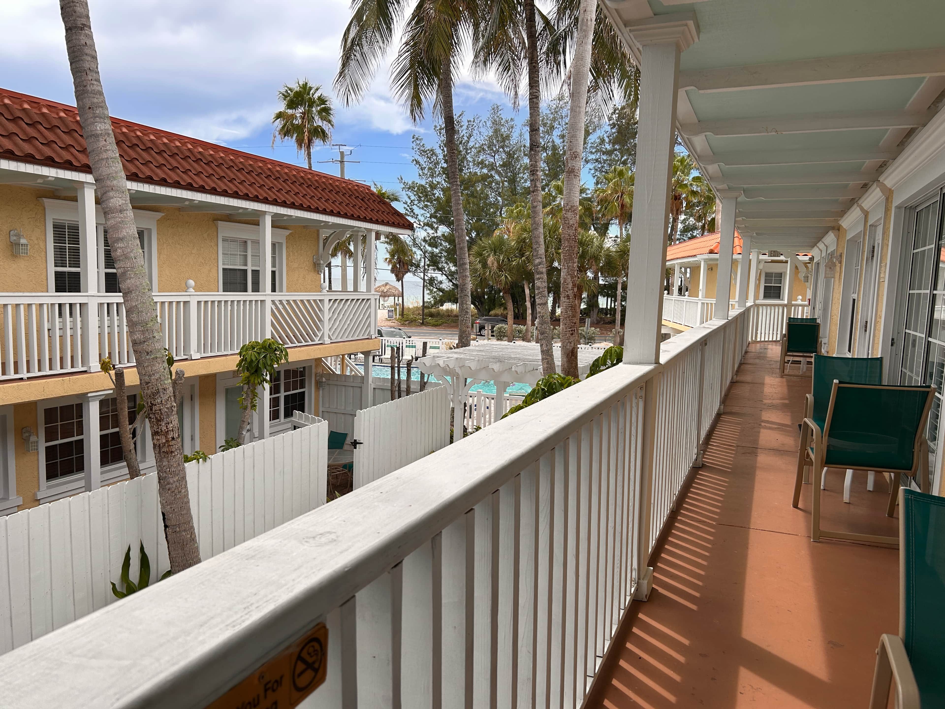 A hotel with a covered outdoor area, a pool, and multiple balconies.