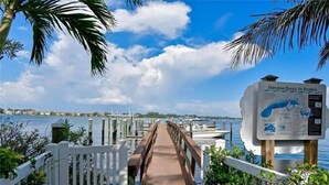 A wooden boardwalk leading to a marina with boats, a sign about Manatee Basics for Boaters, and a clear blue sky. - Tortuga Inn Beach Resort # 229 Island Condo, 2Bdrm (Bradenton Beach)