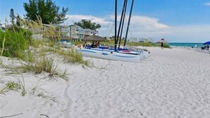 A beach with a row of sailboats docked near a building with a thatched roof. - Tortuga Inn Beach Resort # 229 Island Condo, 2Bdrm (Bradenton Beach)