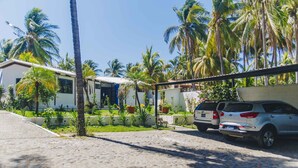 A residential area with a paved driveway, parked cars, and palm trees.