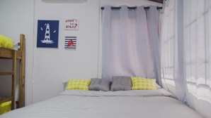 A single bed with a canopy, a bunk bed to the left, and nautical-themed wall art.